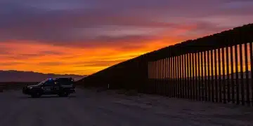 U.S. Border Patrol agent observing the border at sunset, symbolizing increased funding and enhanced security measures.